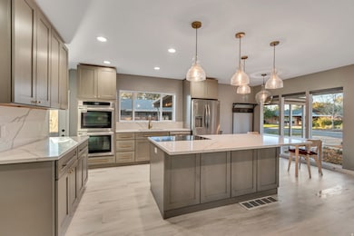Kitchen with hanging light fixtures, stainless steel appliances, light stone countertops, tasteful backsplash, and recessed lighting