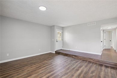 Unfurnished room featuring dark wood-style flooring and a textured ceiling