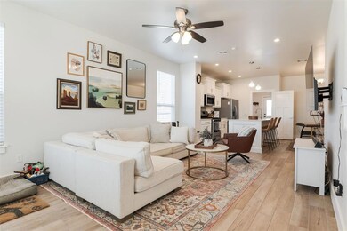 Living room with ceiling fan, sink, and light wood