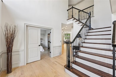 Staircase with wood finished floors, a decorative wall, a wainscoted wall, a high ceiling, and ornamental molding