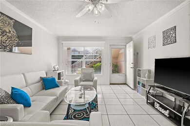 Living area with ornamental molding, tile patterned flooring, a textured ceiling, and ceiling fan