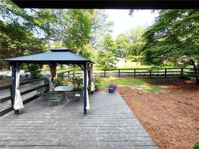 View of front facade with brick siding, driveway, a fenced front yard, and a gazebo