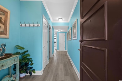 Hall with light wood-style floors, crown molding, 