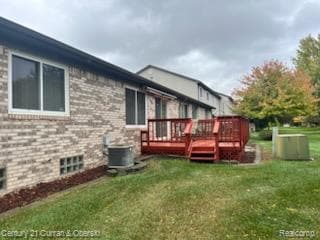 Rear view of house featuring a deck, a yard, and brick siding