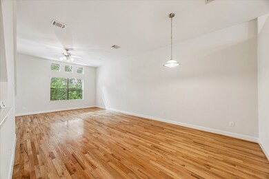 This photo showcases the bright, open-concept layout of the living and dining areas with gleaming hardwood floors and high ceilings.