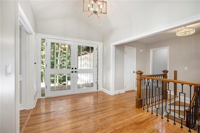 Foyer with a chandelier, french doors, light wood-style floors, and lofted ceiling