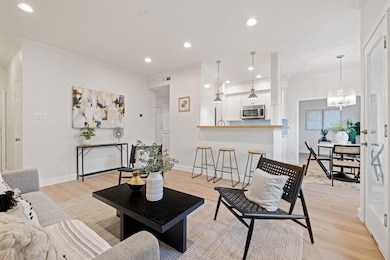 Living room with light wood finished floors, recessed lighting, a chandelier, and ornamental molding