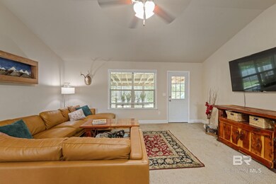 Carpeted living room featuring ceiling fan and vaulted ceiling