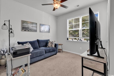 Living area featuring light carpet and ceiling fan