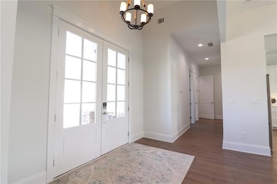 Doorway featuring french doors, dark wood-style floors, baseboards, a chandelier, and recessed lighting