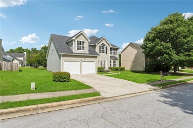 Traditional home featuring concrete driveway, a garage, a front yard, and roof with shingles