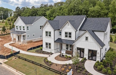 Modern farmhouse style home featuring board and batten siding, roof with shingles, french doors, a standing seam roof, and a metal roof