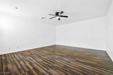 Empty room with dark wood-style floors and ceiling fan