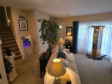 Carpeted living area featuring stairs and plenty of natural light
