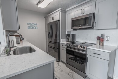 Kitchen with gray cabinetry, light stone counters,