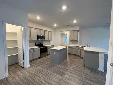 Kitchen featuring a kitchen island, gray cabinets, a sink, and stainless steel appliances