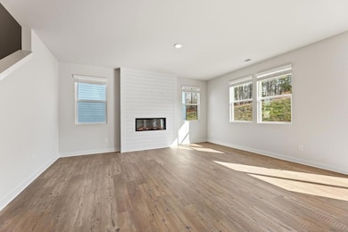 Unfurnished living room featuring wood finished floors and a large fireplace