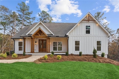Modern farmhouse featuring a shingled roof, board and batten siding, covered porch, and a front lawn