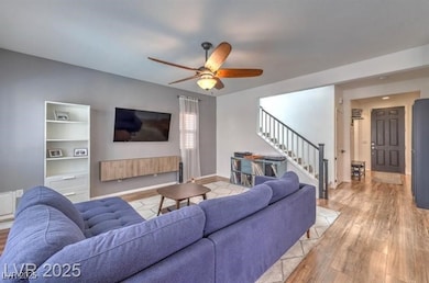 Living area with wood finished floors, stairway, and ceiling fan