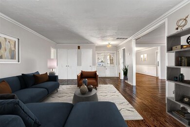 Living room featuring crown molding and dark wood-