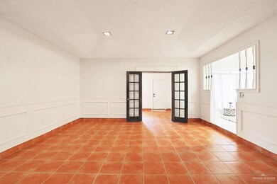 Spare room featuring a decorative wall, french doors, wainscoting, tile patterned floors, and a textured ceiling