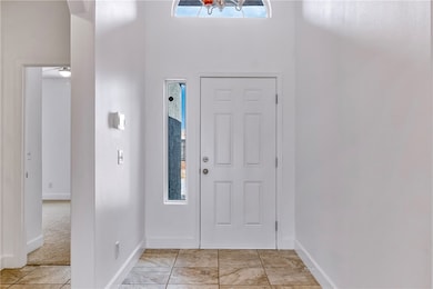 Foyer with baseboards and a high ceiling