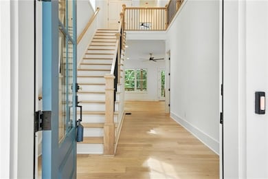 Entryway with stairway, light wood-style flooring, and a towering ceiling