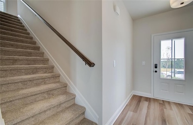 Foyer entrance featuring stairway, light wood-style flooring, and baseboards