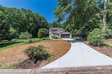 View of front of property featuring concrete driveway, a front yard, and an attached garage