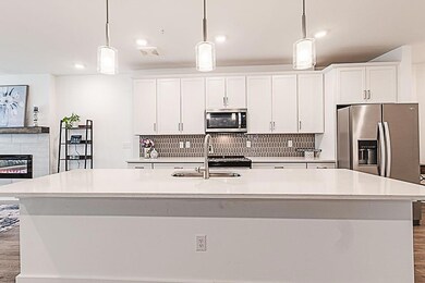 Kitchen with an island with sink, white cabinetry,