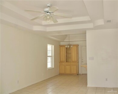 Unfurnished room featuring a raised ceiling, light tile patterned floors, a ceiling fan, and a chandelier
