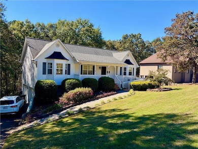 View of front of house with a porch, a front lawn, a shingled roof, and an attached garage