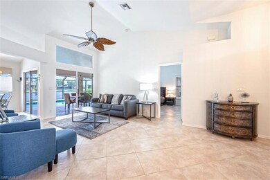Living area featuring a ceiling fan, light tile patterned floors, high vaulted ceiling, and baseboards