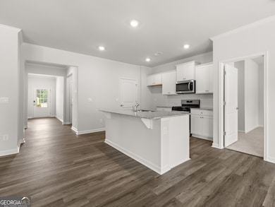 Aria kitchen with access to the front entry hallway and hardwood like flooring with a large center island