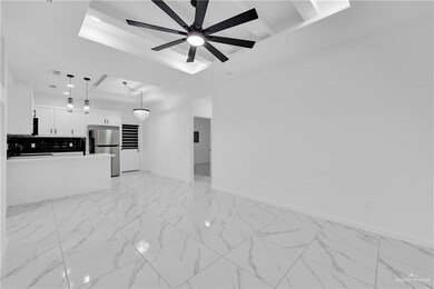 Unfurnished living room featuring ceiling fan, sink, and a tray ceiling