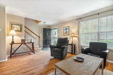 Living room featuring a healthy amount of sunlight, wood-type flooring, and ornamental molding