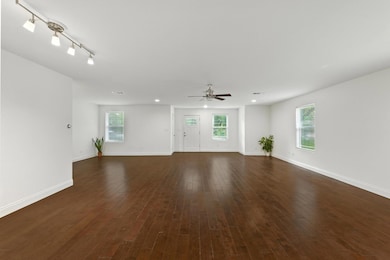 Unfurnished living room with ceiling fan, dark wo