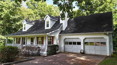 Cape cod-style house featuring a porch, a garage, driveway, and roof with shingles