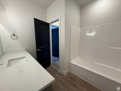 Full bath featuring vanity, bathing tub / shower combination, and dark wood-style floors
