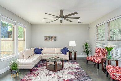 Living room with concrete flooring, a ceiling fan