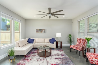 Living room with concrete flooring, a ceiling fan