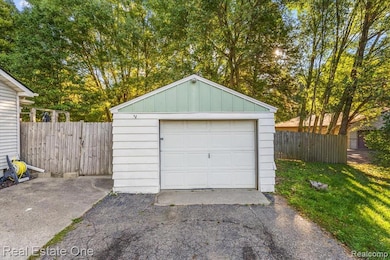 Detached garage with asphalt driveway and view of scattered trees
