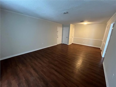 Empty room with a textured ceiling, crown molding,