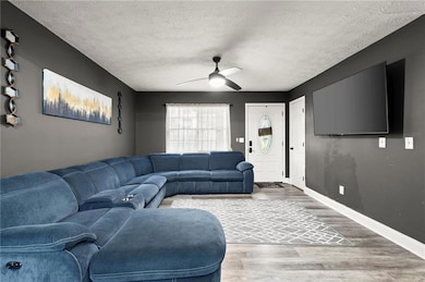Living area featuring wood finished floors, a textured ceiling, and a ceiling fan
