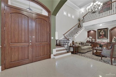 Entryway featuring arched walkways, stairs, a high ceiling, crown molding, and a chandelier