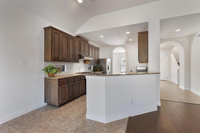 Kitchen with dark brown cabinets, light stone cou