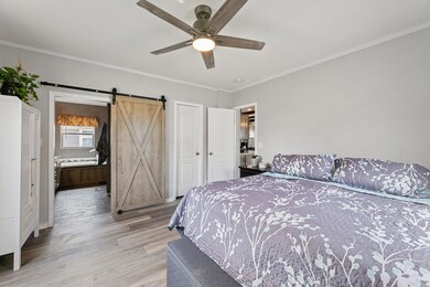 Bedroom featuring a barn door, light wood-style f