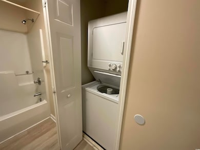 Laundry area featuring stacked washing machine and dryer and light wood-type flooring