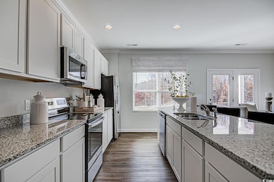Kitchen featuring visible vents, light stone countertops, ornamental molding, stainless steel appliances, and a sink