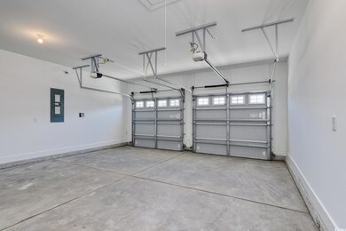 Garage featuring electric panel, a garage door opener, and baseboards